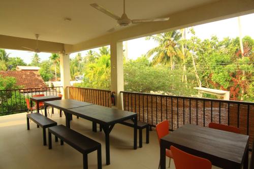 two tables and chairs on a balcony with windows at JJ's Hostel Mirissa in Mirissa