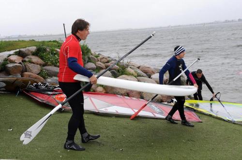 tre persone stanno remando una barca in acqua di Ferienwohnung Zwergmöwe In Neue Tiefe a Fehmarn