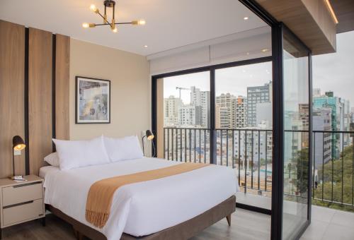 une chambre avec un grand lit et une grande fenêtre dans l'établissement Alameda by Wynwood House, à Lima
