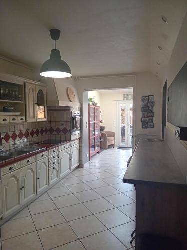 une cuisine avec des armoires blanches et un sol carrelé dans l'établissement Maison proche du circuit des 24h du Mans, à Mulsanne