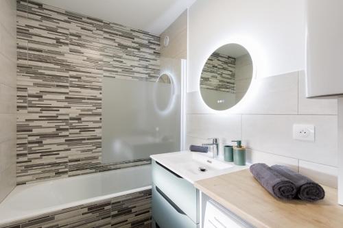 La salle de bains blanche est pourvue d'un lavabo et d'une baignoire. dans l'établissement Plein centre, calme et lumineux, à Mandelieu-la-Napoule