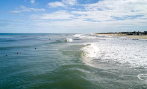 a group of people surfing in the ocean at Buxton Slick - Waterfront 2-Bedroom, 2-Bathroom Suite at REAL Watersports in Waves