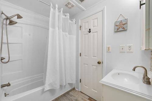 a white bathroom with a shower curtain and a sink at The Iron Seahorse Orlop Surf City Condo in Surf City