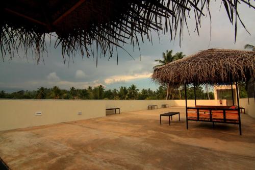 a pavilion with a picnic table and a straw umbrella at JJ's Hostel Mirissa in Mirissa