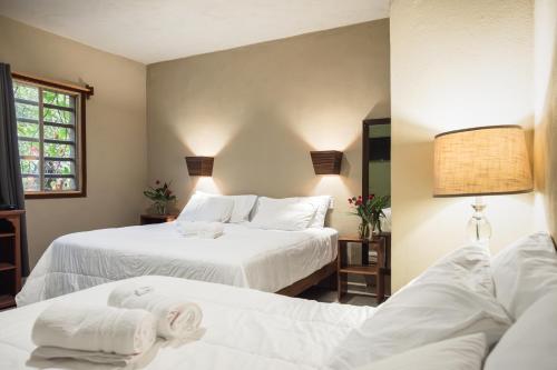two beds in a room with white sheets at Hokhmah Heart Hotel in Puerto Morelos