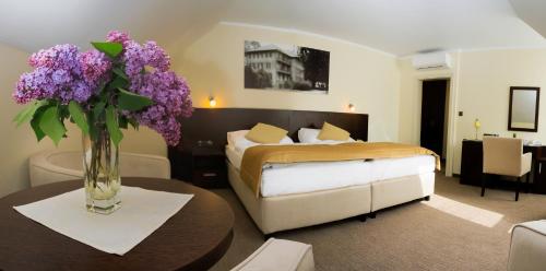 a bedroom with a bed and a vase of purple flowers on a table at Ensana Pro Patria in Piešťany