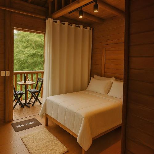 a bedroom with a bed and a balcony with a table at Natural Harmony Bungalow in Baturité