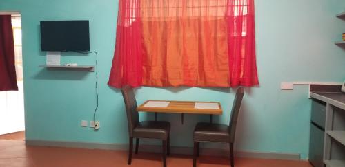 a small table and chair in a room with a red curtain at Careffe Suites St Lucia in Monchy