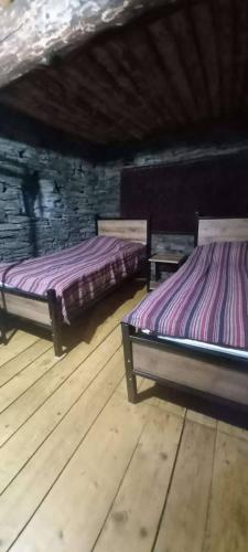 two beds in a room with wooden floors at Hotel Front Castle in Shatili