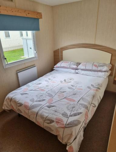 a bedroom with a bed with a floral bedspread at Meadow Lakes 39 in Skegness