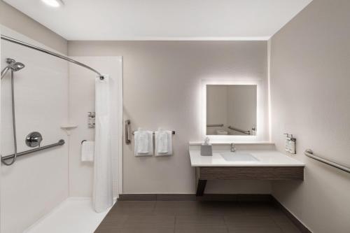 a white bathroom with a sink and a mirror at Holiday Inn Express & Suites Boynton Beach West by IHG in Boynton Beach