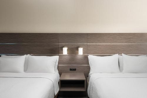 two beds with white pillows in a hotel room at Holiday Inn Express & Suites Boynton Beach West by IHG in Boynton Beach