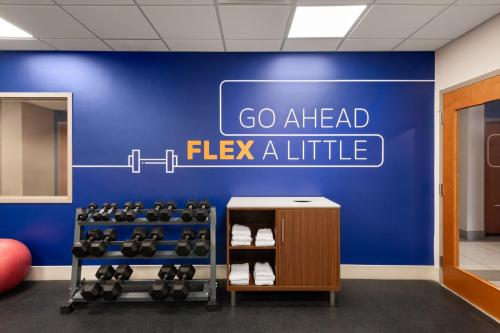 a gym with a wall with a sign that says go ahead flex aittle at Holiday Inn Express & Suites Boynton Beach West by IHG in Boynton Beach