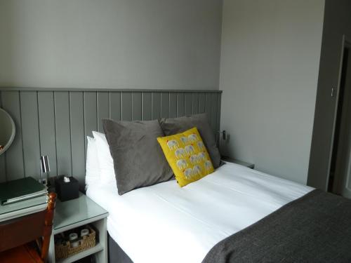 a bed with a yellow pillow on top of it at Edgar Townhouse in Bath