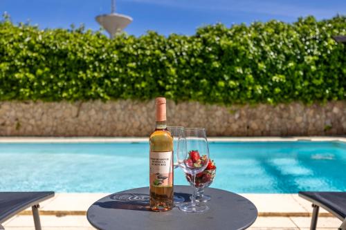 a bottle of wine and a glass on a table by a pool at Montinhos Nature Stay in Luz