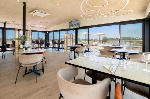 un restaurant avec des tables, des chaises et des fenêtres dans l'établissement Golden Tulip Hotel & Rooftop Martigues Provence, à Martigues
