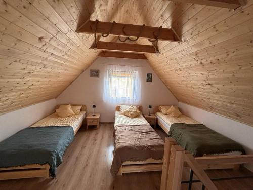 a attic room with three beds and a window at Pod Roztoczańskim Niebem in Wólka Wieprzecka
