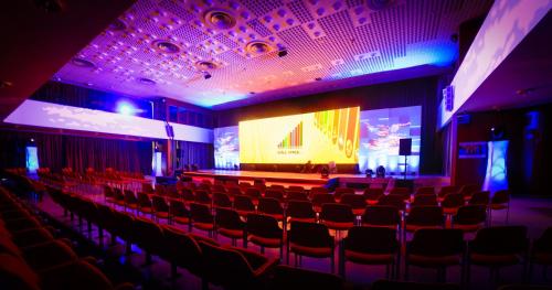 a theatre with red chairs and a stage with a screen at Ensana Pro Patria in Piešťany