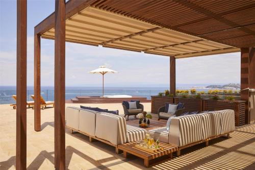 a patio with couches and an umbrella and the ocean at Kempinski Hotel Adriatic Istria Croatia in Savudrija