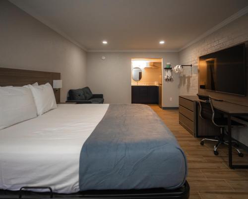 a hotel room with a bed and a desk and a television at Economy Suites Extended Stay in Tulsa