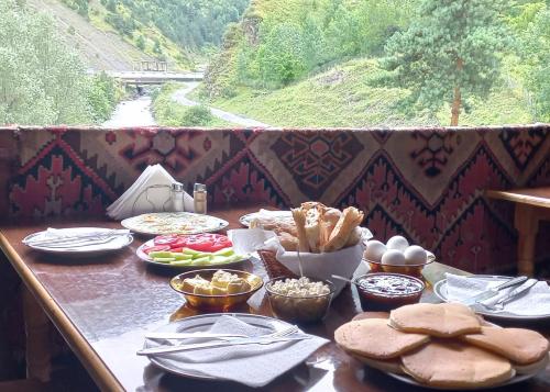 a table with food on it with a view of a river at Hotel Front Castle in Shatili