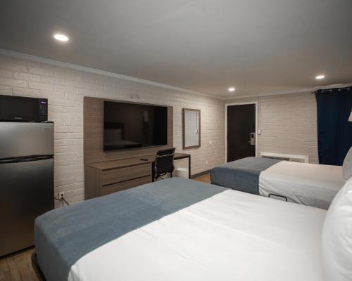 a hotel room with two beds and a flat screen tv at Economy Suites Extended Stay in Tulsa