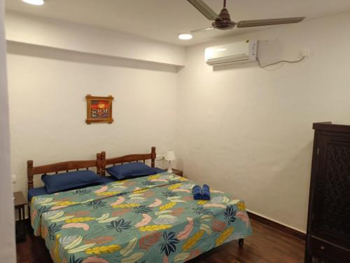 a bedroom with a bed with a colorful comforter and a fan at 4BHK Private Pool villa in North Goa with Kayaking nearby!! in Moira