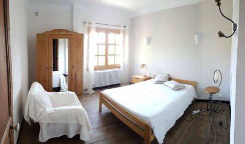 une chambre blanche avec un lit et une chaise dans l'établissement Mas en Provence, à Graveson
