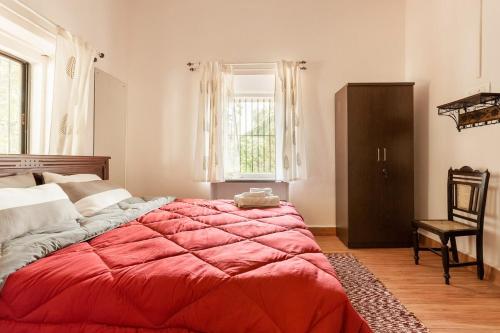 a bedroom with a large red bed and a chair at 4BHK Private Pool villa in North Goa with Kayaking nearby!! in Moira