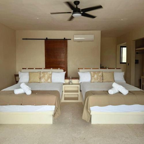 a bedroom with two beds and a ceiling fan at DK Luxury Ocean Front Villa - Adults Only in Holbox Island