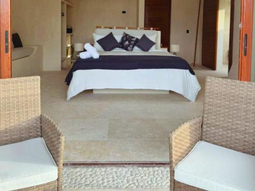 a bedroom with a large bed and two chairs at DK Luxury Ocean Front Villa - Adults Only in Holbox Island