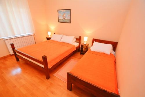 two beds in a small room with two lamps at Apartments Soso in Kotor