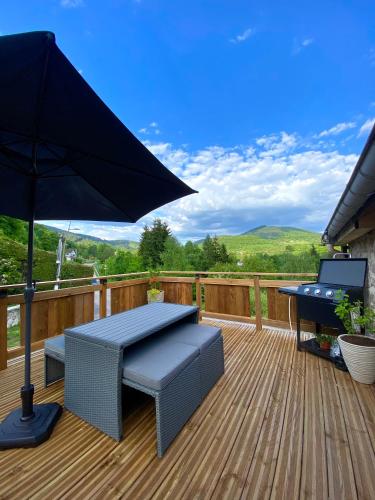 a patio with a table and an umbrella on a deck at Gîtes les cocons des guédons Le Douglas in Le Ménil