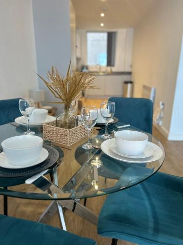 a glass table with plates and wine glasses on it at Manchester Central - Modern Apartment - Free Parking in Manchester