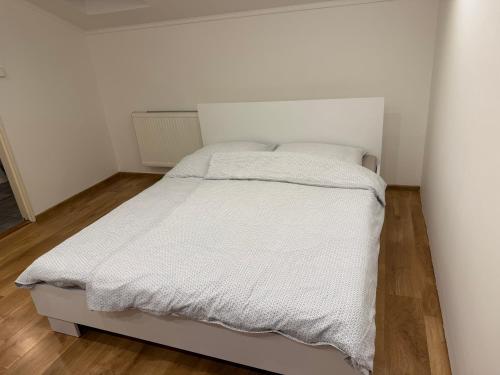 a white bed in a white bedroom with wooden floors at Ubytovanie Stavbar in Štúrovo