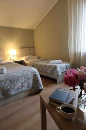 a hotel room with two beds and a table with a book at Lavitor hotel in Bishkek