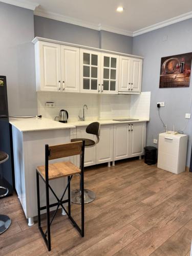 une cuisine avec des armoires blanches et une table et une chaise dans l'établissement Metrocity residence d, à Batoumi