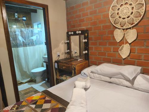 a bedroom with a bed and a brick wall at Pousada Tarumã challes 3 in Bonito