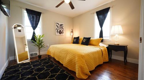 een slaapkamer met een bed met een geel dekbed en een spiegel bij Honey Pot House in Novi