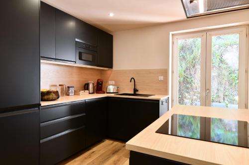 une cuisine avec des armoires noires et une fenêtre dans l'établissement Au Paradis des 4 Saisons - Maison avec terrasse, à Moosch