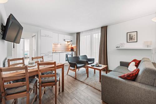 a living room with a couch and a table and a kitchen at Herzblut Wohlfühl Appartements in Oetz