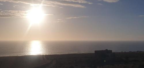 a sun is shining over the ocean on a beach at Douira Nature in Douaïra