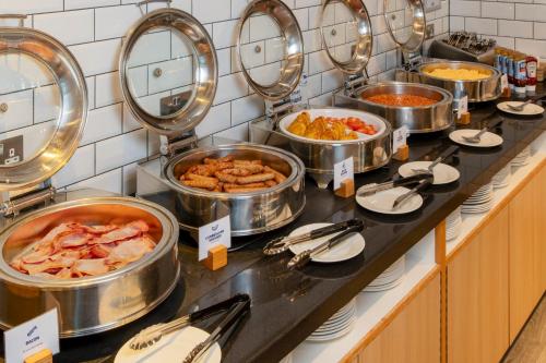 a buffet line with many pots and pans of food at Holiday Inn Express London - Epsom Downs by IHG in Epsom