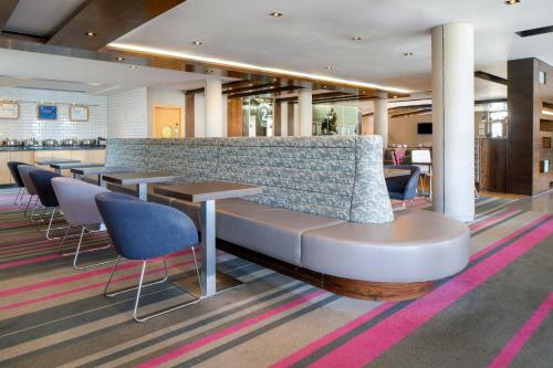 a lobby with a bench and tables and chairs at Holiday Inn Express London - Epsom Downs by IHG in Epsom