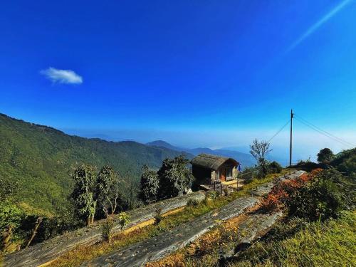 a house on the side of a hill with a mountain at The92dowhill farmhouse in Kurseong
