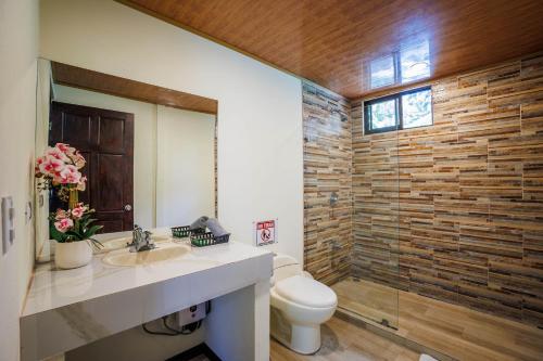 a bathroom with a toilet and a sink and a mirror at Bambutel Cocles in Puerto Viejo