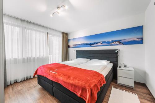 a bedroom with a large bed with a red blanket on it at Herzblut Wohlfühl Appartements in Oetz
