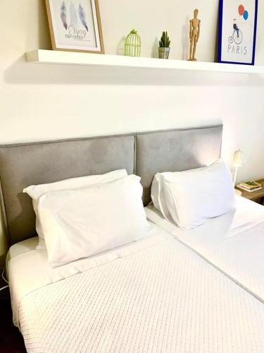a bed with white sheets and pillows on it at Yellow Five Apartment in Ponta Delgada