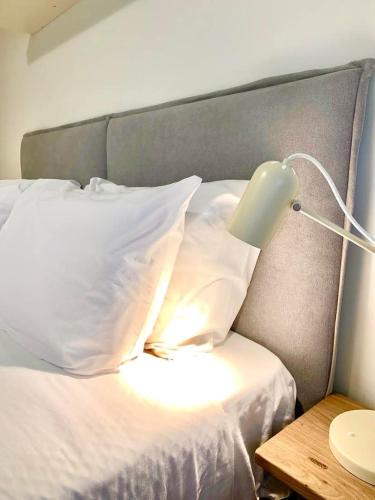 a bed with white pillows and a lamp on a table at Yellow Five Apartment in Ponta Delgada