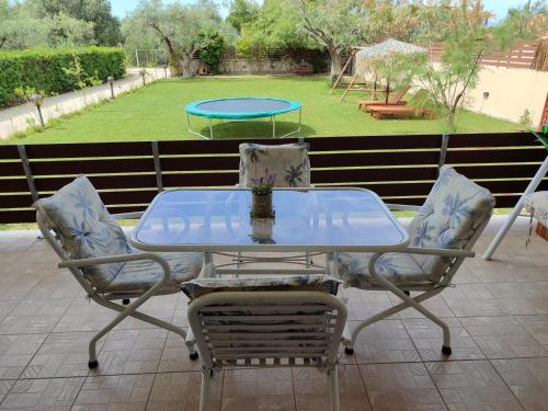 a glass table and chairs on a patio with a trampoline at George's family friendly maisonette with great exterior in Drosia